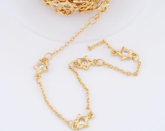 May include: Gold-colored chain with star-shaped charms, each featuring a clear, round gemstone. The chain is shown in a roll and also in a separate strand, ideal for jewelry making or crafting projects.