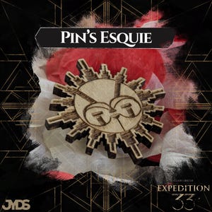 Op de afbeelding: Houten speld met een zonontwerp, met een gezicht met een bril. De speld is omgeven door een zonnestralenpatroon. De tekst "PIN'S ESQUIE" staat bovenaan. De speld staat op een achtergrond van rode en witte stof.