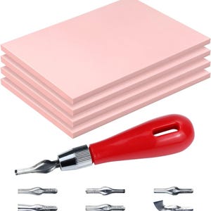 May include: A set of pink linoleum carving blocks with a red-handled linocut tool and several interchangeable blades. The linocut tool has a silver metal tip and a red handle. The pink blocks are stacked in a neat pile, ready for printmaking.