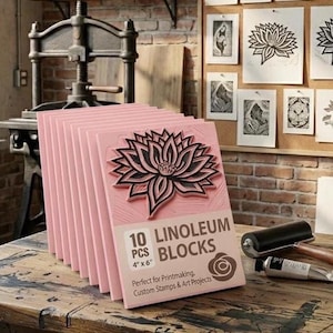 May include: A stack of ten pink linoleum blocks for printmaking, each measuring 4 inches by 6 inches. The front block features a carved lotus flower design and text that reads 10 PCS LINOLEUM BLOCKS. A black brayer and a tube of paint are nearby.