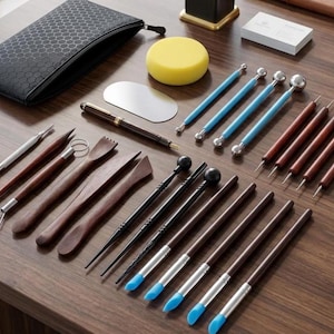 May include: A comprehensive clay sculpting tool set including wooden modeling sticks, metal ball styluses with blue handles, silicone-tipped brushes, a black zippered storage case, a yellow circular sponge, a metal scraper, and a dark brown pen.