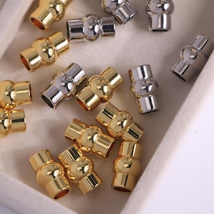 May include: A selection of gold and silver magnetic clasps. The clasps are barrel-shaped with a magnetic closure. These metal clasps are designed for jewellery making and crafting projects.