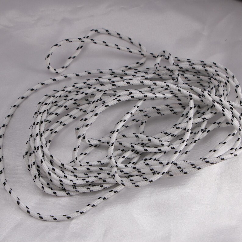 May include: White rope with a repeating pattern of small black dashes. The rope is coiled and appears to be made of a durable material, suitable for various uses. The rope is against a white background.
