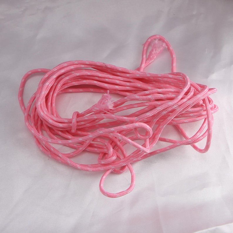 May include: A tangled bundle of pink and white patterned rope. The rope is a vibrant pink color with a subtle white pattern throughout. The rope is coiled and knotted, suggesting it is ready for use.