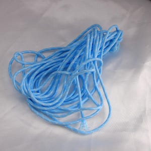 May include: A tangled coil of light blue rope with a white speckled pattern. The rope is tightly wound and appears to be made of a durable, flexible material. The background is a plain white surface.