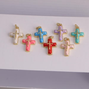 Peut inclure: Une collection de pendentifs croix colorés. Chaque croix présente un contour et une bélière dorés, avec une finition émaillée vibrante dans des tons de blanc, rose, bleu, rouge, violet et sarcelle. Les croix sont conçues pour la fabrication de bijoux.
