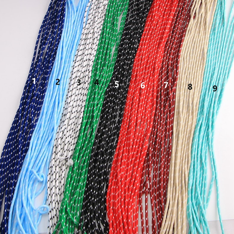 May include: Nine colorful cords in shades of blue, light blue, white, green, black, red, brown, beige, and turquoise. Each cord is tightly woven with a contrasting dotted pattern. The cords are arranged side by side.