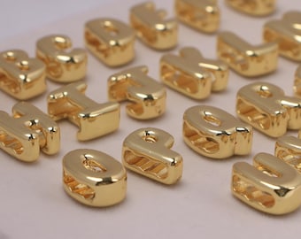 May include: Gold-colored alphabet letter beads. The beads are in various letters, including the letters B, H, I, O, P, R, and U. The beads have a shiny, metallic finish and are likely used for jewelry making or crafts.