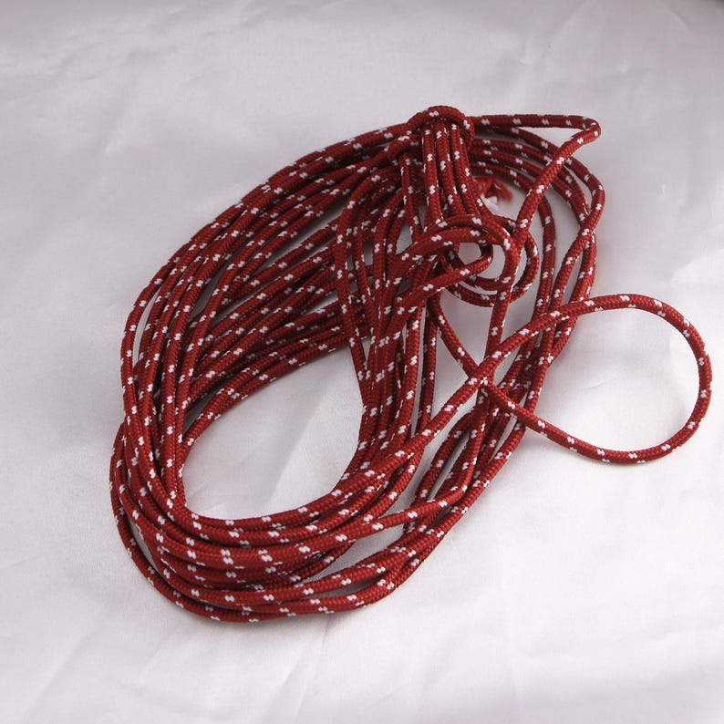 May include: A coil of red rope with a white dotted pattern. The rope is tightly wound and appears to be made of a durable material. The rope is suitable for various crafting and outdoor projects.