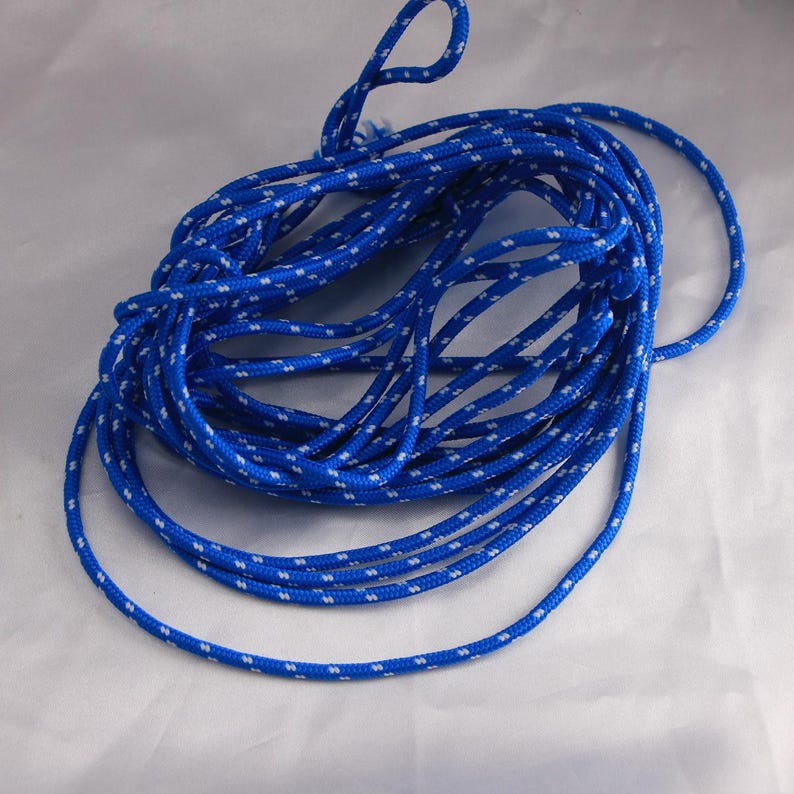 May include: Coiled blue rope with white dotted pattern. The rope is tightly wound, with a loop at the top. The rope is likely used for various outdoor activities.