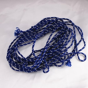 May include: Coiled blue and white rope. The rope is a deep blue color with a repeating pattern of small white dots. The rope is knotted at the ends and appears to be made of a durable material. The rope is suitable for various crafting and decorative purposes.