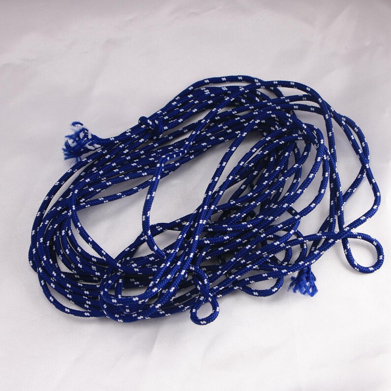 May include: Coiled blue and white rope. The rope is a deep blue color with a repeating pattern of small white dots. The rope is knotted at the ends and appears to be made of a durable material. The rope is suitable for various crafting and decorative purposes.