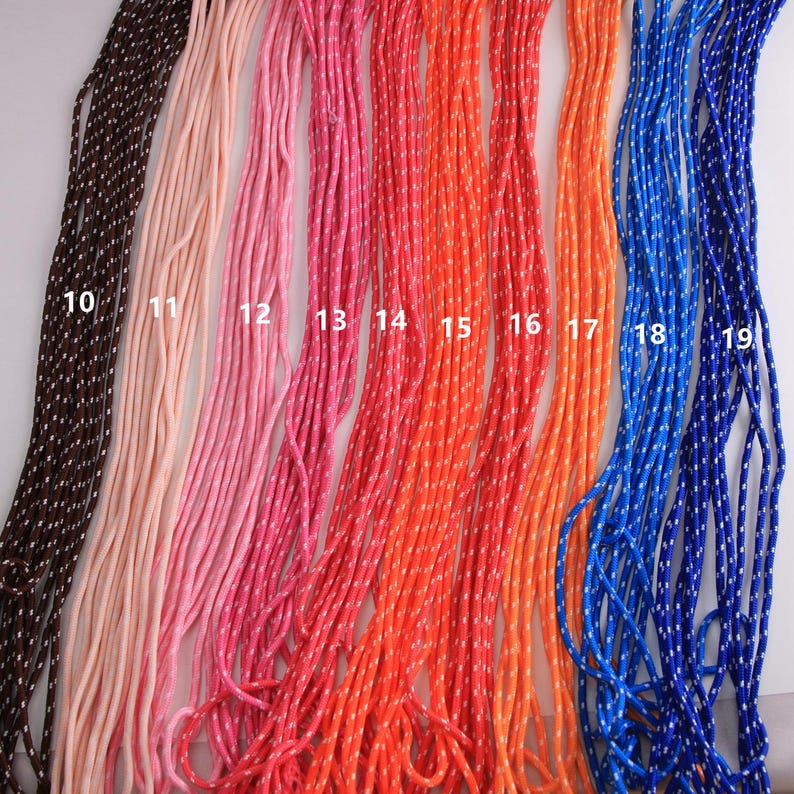 May include: A collection of colorful cords in various shades, including brown, pink, red, orange, and blue. Each cord is a different color and has a white dotted pattern. The cords are arranged vertically, showcasing a range of hues.