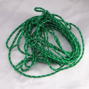 May include: A tangled coil of green rope with a white dotted pattern. The rope is thick and appears to be made of a durable material. The rope is suitable for various outdoor and crafting purposes.