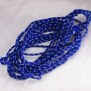 May include: A length of blue rope with a white dotted pattern. The rope is coiled and knotted at one end. The rope is made of a durable material and is suitable for various uses.