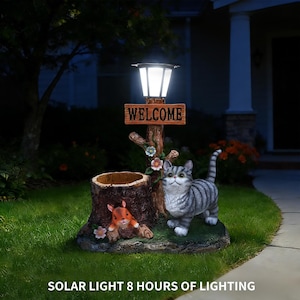 Może przedstawiać: Ozdobna solarna lampa ogrodowa z szarą figurką kota pręgowanego, wiewiórką i drewnianym znakiem z napisem "WELCOME". Światło jest zamontowane na sztucznym pniu drzewa z lampą solarną. Tekst "SOLAR LIGHT 8 HOURS OF LIGHTING" znajduje się na dole.