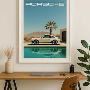 May include: A framed print featuring a white Porsche sports car parked by a turquoise pool under a clear blue sky. The word "PORSCHE" is printed at the top. A palm tree and desert landscape are in the background.