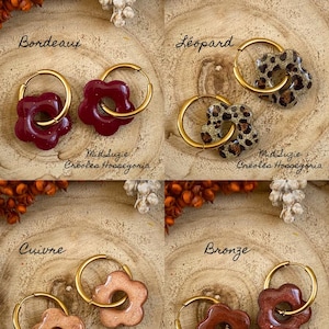May include: Four pairs of flower-shaped earrings with gold hoops. The earrings come in four colors: burgundy, leopard print, copper, and bronze. The text "Bordeaux", "L&eacute;opard", "Cuivre", and "Bronze" are written above each pair of earrings. The text "Mid Suzie Cr&eacute;oles Hossegoria" is written below each pair.