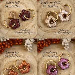 May include: Four pairs of flower-shaped earrings with gold hoops. The earrings are in shades of brown, beige, orange, and purple, with glitter accents. The text on the image reads "Chocolat Paillettes", "Caf&eacute; au lait Paillettes", "Pumpkin Paillettes", and "Bordeaux Paillettes".