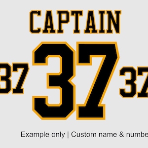 May include: A white background with the word "CAPTAIN" in bold, black letters with yellow trim. The number "37" is displayed three times in black with yellow trim. The text "Example only | Custom name & number" is below the numbers.