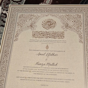 May include: A formal marriage certificate with ornate gold and brown decorative borders. The document features Arabic calligraphy and English text, including the names Amal Iftikhar and Humza Mallick. The certificate is a testament to a marriage solemnized under Islamic law.