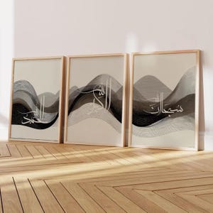 Puede incluir: Tres impresiones artísticas enmarcadas con diseños de ondas abstractas en tonos grises y negros. Cada impresión presenta caligrafía árabe blanca. Los marcos son de madera clara y el fondo es beige neutro.