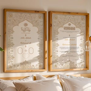 May include: Two rectangular wooden frames containing off-white wedding certificates with intricate gold floral borders. The left print features Arabic calligraphy, the names Aisha Abubakr and Muhammad Ali, and a heart icon. The right print displays text.