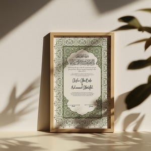 May include: A framed print featuring Arabic calligraphy and English text. The print has a light green and cream color scheme with decorative borders. The names "Aisha Abu Bakr" and "Muhammad Abdullah" are written in elegant script.