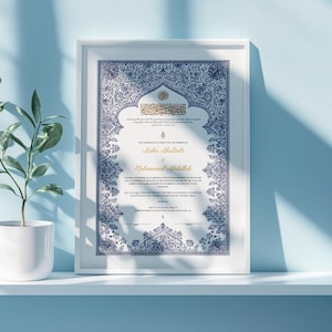 May include: A framed Islamic marriage certificate featuring intricate blue and white floral border patterns. The document includes gold-colored text for the names Aisha AbuBakr and Muhammad Abdullah, with additional printed text in English and Arabic.
