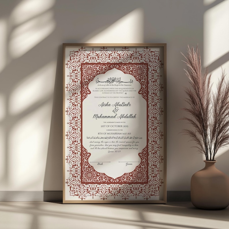 May include: Framed wedding certificate with ornate red and white design. The names Aisha AbuBakr and Muhammad Abdullah are featured, along with the date October 25, 2015. The frame is a light brown color.