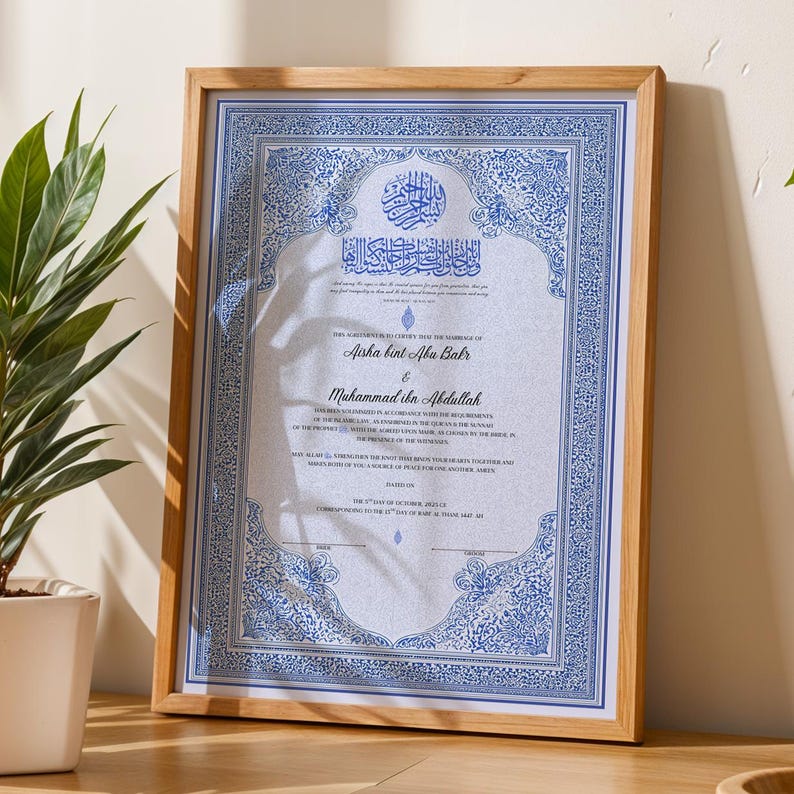 May include: A framed marriage certificate with ornate blue and white designs. The certificate includes Arabic calligraphy and the names Aisha bint Abu Bakr and Muhammad ibn Abdullah. The frame is made of light-colored wood.