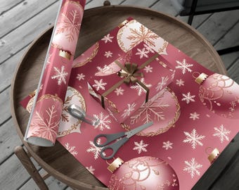 May include: A roll of red wrapping paper with a Christmas ornament design, a wrapped gift, and scissors on a wooden table. The wrapping paper and gift box feature gold snowflakes and ornament illustrations.