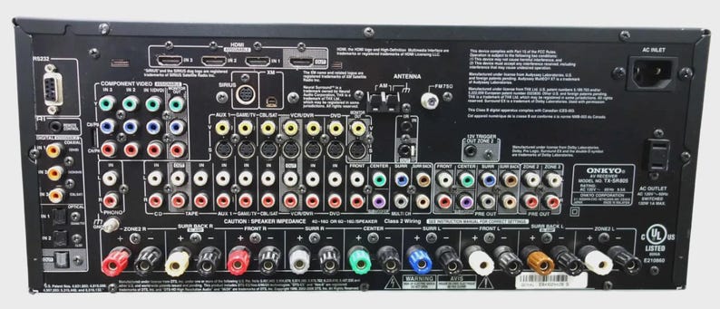May include: The black rear panel of an Onkyo TX-SR805 AV receiver featuring numerous input and output ports, including HDMI, component video, digital audio, and speaker terminals, with printed technical specifications and regulatory markings.