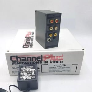 May include: A black Channel Plus video modulator with multiple input and output ports, sitting on a white box with the text "Channel Plus INNOVATIONS IN VIDEO". An AC adapter is also present.