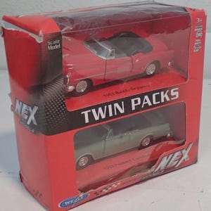 Op de afbeelding: Een rode doos met twee schaalmodel auto's, een rode en een groene cabriolet. De doos leest "TWIN PACKS" en bevat de tekst "1953 Buick Skylark" en "1953 Packard Caribbean". De doos is gelabeld "NEX MODELS".