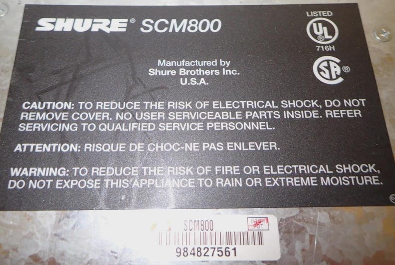 May include: A black label with white text for a Shure SCM800 audio product. The label includes safety warnings, manufacturer information, and UL and SP certifications. A sticker with a barcode and the product model is also present.