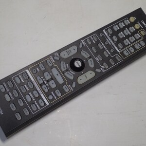 May include: A black Onkyo RC-623M remote control featuring a rectangular body with numerous grey buttons for device operation, including volume, playback, and input selection controls, with white text labels printed on the surface of the device.