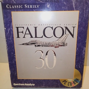 Op de afbeelding: Een blauwe doos voor het "FALCON 3.0" pc cd-rom spel. De doos toont de tekst "CLASSIC SERIES" en "ELECTRONIC BATTLEFIELD SERIES". De titel van het spel en een straaljager staan op een zilveren achtergrond.