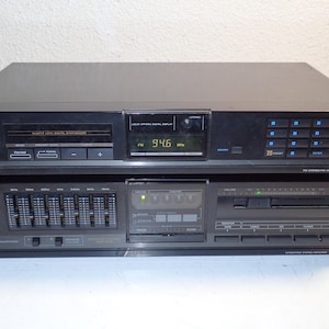 Puede incluir: Dos componentes de audio Sony negros apilados. El componente superior es un sintonizador con una pantalla digital que muestra "94.6 MHz", y el componente inferior es un amplificador con controles de ecualizador.