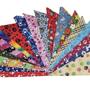 May include: A collection of colorful dog bandanas, each with a unique pattern. Designs include paw prints, bones, floral, and dog illustrations. The bandanas are arranged in a fan shape, showcasing the variety of styles.