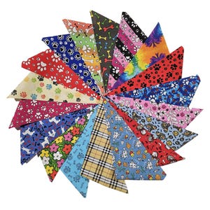 May include: A selection of triangular dog bandanas in a circular arrangement. The bandanas display diverse patterns such as paw prints, bones, floral motifs, and plaid. The colour scheme includes red, blue, pink, yellow, and green.