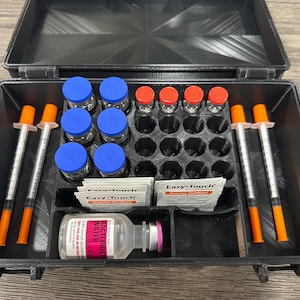 May include: A black plastic case with an open lid, containing vials with blue and red caps, syringes, and packets. The case is organized with compartments for the various medical supplies. The label on the bottle reads "Bacteriostatic Water".