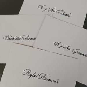 Puede incluir: Varias tarjetas blancas con elegante caligrafía negra. Se ven los nombres "Sr. y Sra. Estrada", "Elisabetta Bracco", "Sr. y Sra. Gomendio" y "Rafael Hernando". Las tarjetas están dispuestas en una composición en capas.
