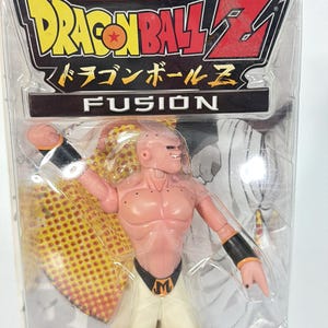 May include: A Dragon Ball Z Fusion action figure of the character Buu, encased in original plastic packaging. The figure is pink with a muscular build, wearing white pants and a black belt with an M emblem. The packaging features the Dragon Ball Z logo.
