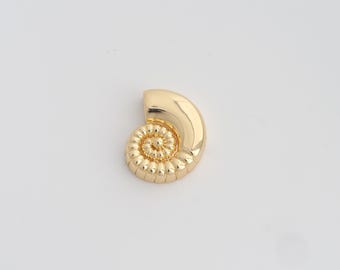 May include: A gold-colored, nautilus-shaped decorative object. The object has a polished, smooth surface on the outer curve and a detailed, textured spiral pattern on the inner portion. The design is reminiscent of a seashell.