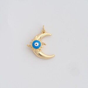 May include: Gold-colored pendant featuring a crescent moon design with a sunburst and an evil eye. The evil eye has a blue iris and a white pupil. The pendant is likely made of metal and has a small loop for a chain.
