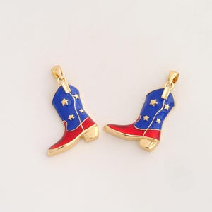 May include: Two gold-toned metal pendants shaped like cowboy boots. Each boot features a glossy blue upper section decorated with small gold stars and a vibrant red lower section. A small gold loop is attached to the top of each boot pendant.