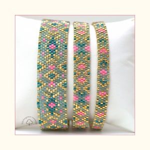 Peut inclure: Trois bracelets perlés avec un motif géométrique. Les bracelets présentent un motif répétitif de formes roses et turquoise sur un fond gris, accentué de perles dorées. Les bracelets sont présentés sur une surface blanche.
