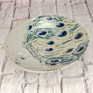 Ciotola decorativa in ceramica vintage anni '90, realizzata a mano con piuma di pavone e firma artistica.