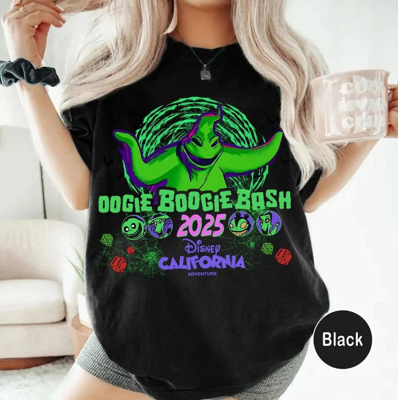 Op de afbeelding: Een zwart t-shirt met een felgroene afbeelding van Oogie Boogie uit The Nightmare Before Christmas. Het ontwerp bevat de tekst Oogie Boogie Bash 2025, Disney California Adventure en kleine illustraties van dobbelstenen, spinnenwebben en personages.